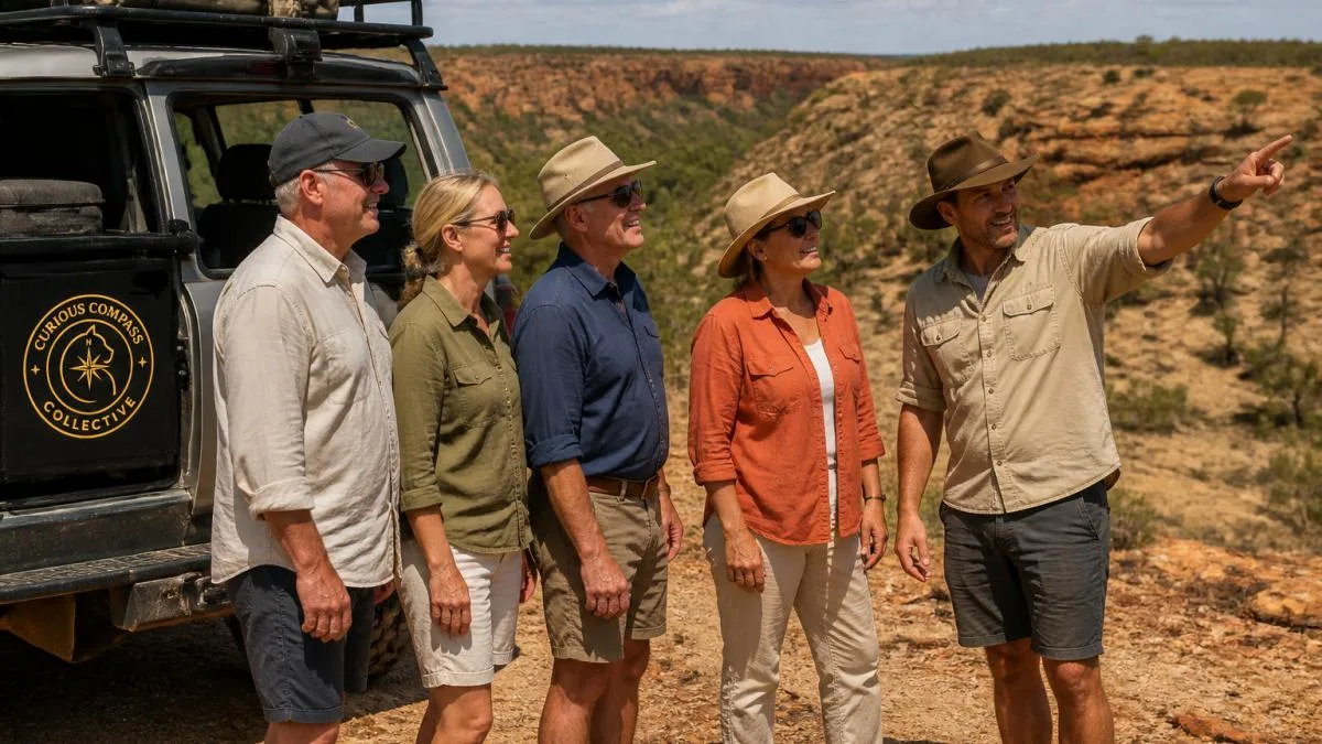 Small group of mature travellers standing beside a purpose-designed 4WD vehicle in rugged outback terrain, smiling and engaged with an expert guide pointing toward the landscape